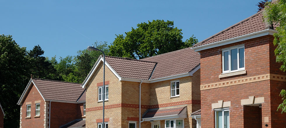 Suburban houses with brick facades and brown tiled roofs under a clear blue sky