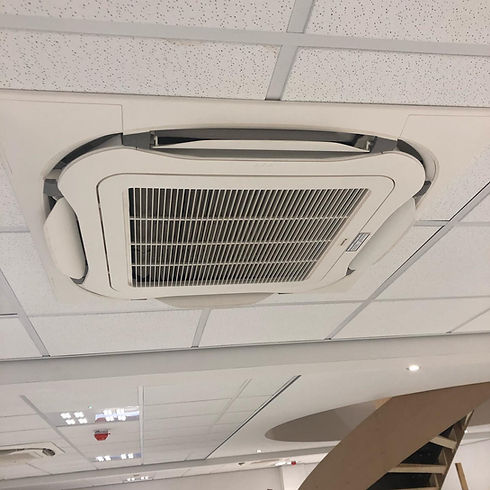 Ceiling-mounted air conditioning unit with a large vent, set within a grid of white ceiling tiles