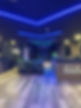 Modern health club reception area featuring wooden floors, neon lighting, and a sleek front desk