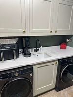 A stylish laundry area with modern appliances and gold-knob cabinetry