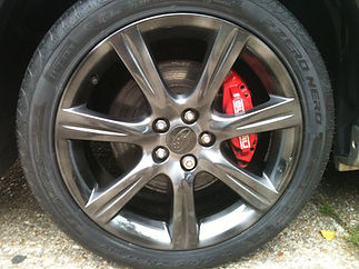 Close-up of a sleek black alloy wheel paired with vibrant red brake calliper