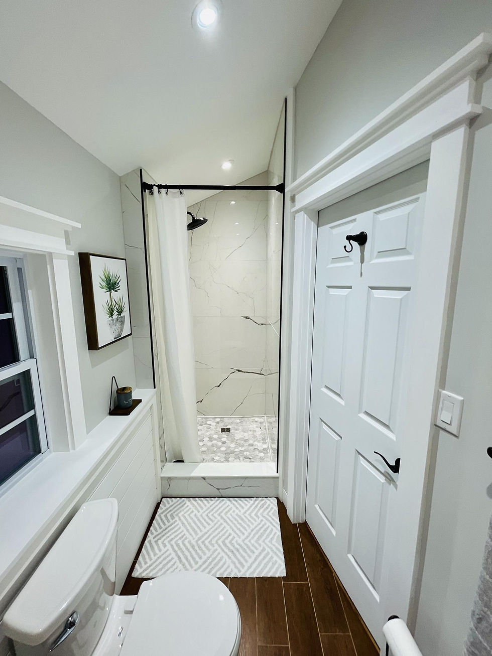 Finished bathroom renovation with custom tiled shower, white trim work, solid core door, black hardw