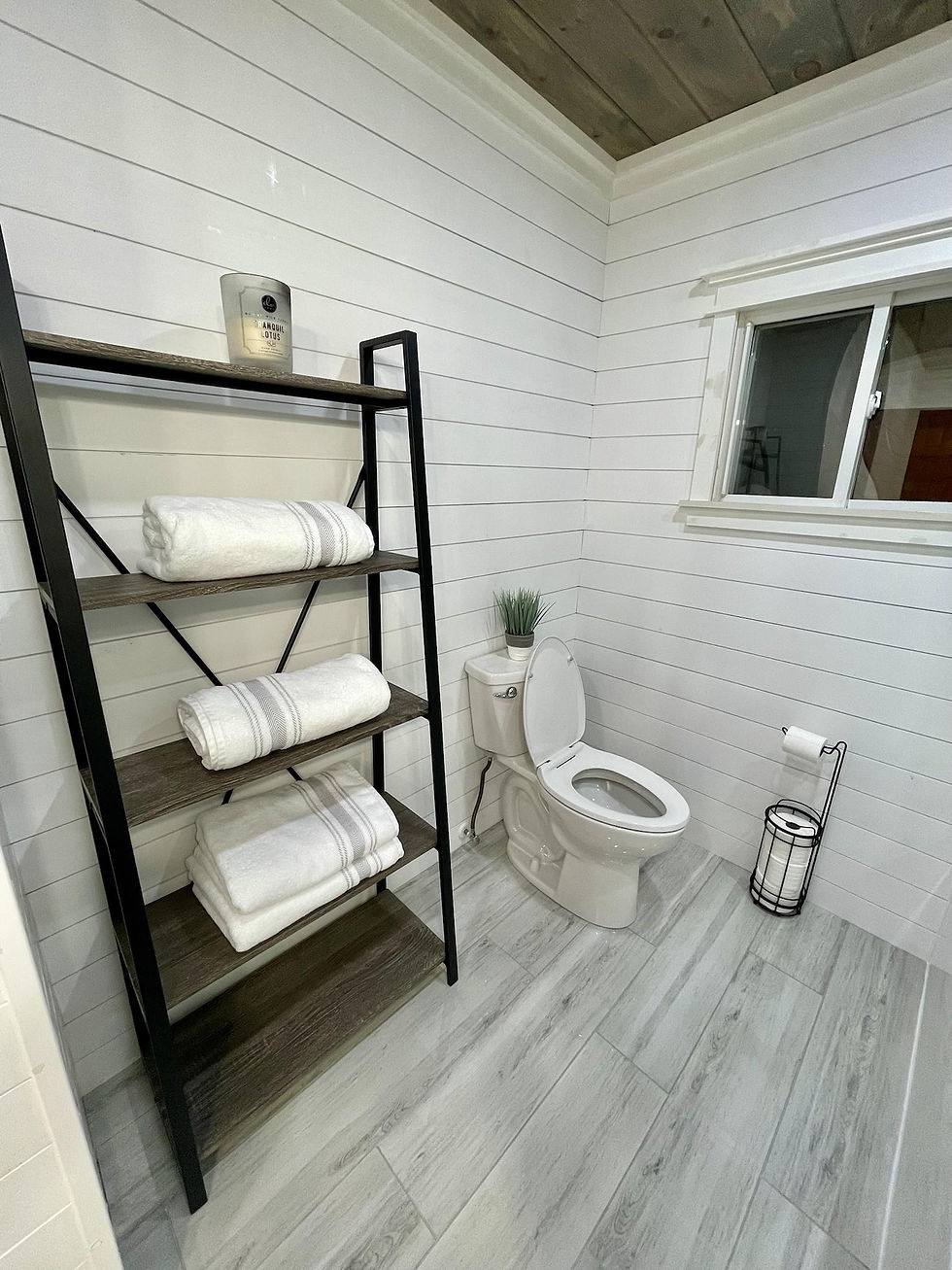 Finished bathroom with white shiplap walls and wood-look tile floor.