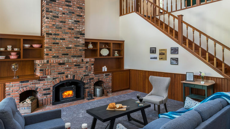 Inviting common area with a brick fireplace, comfortable seating, and warm wood accents at Gardenview Estate.