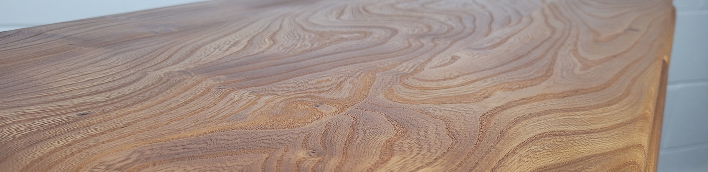 Close-up of shaped wooden handles and elm grain on an Ercol cabinet drawer