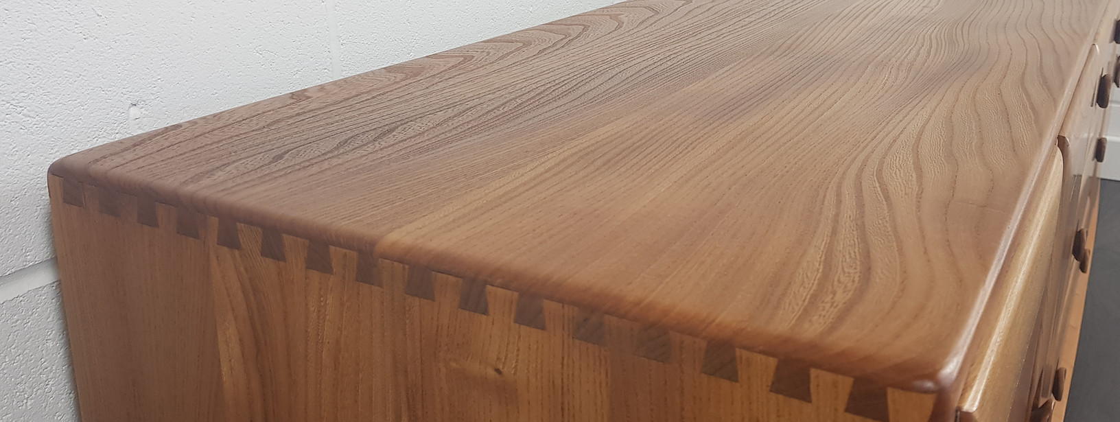 Close-up of exposed dovetail joints and elm grain on an Ercol cabinet