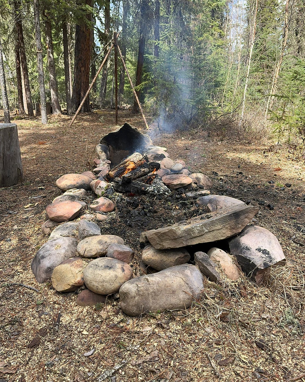 a large campfire ringed by boulders. smoke is wafting into the air. 