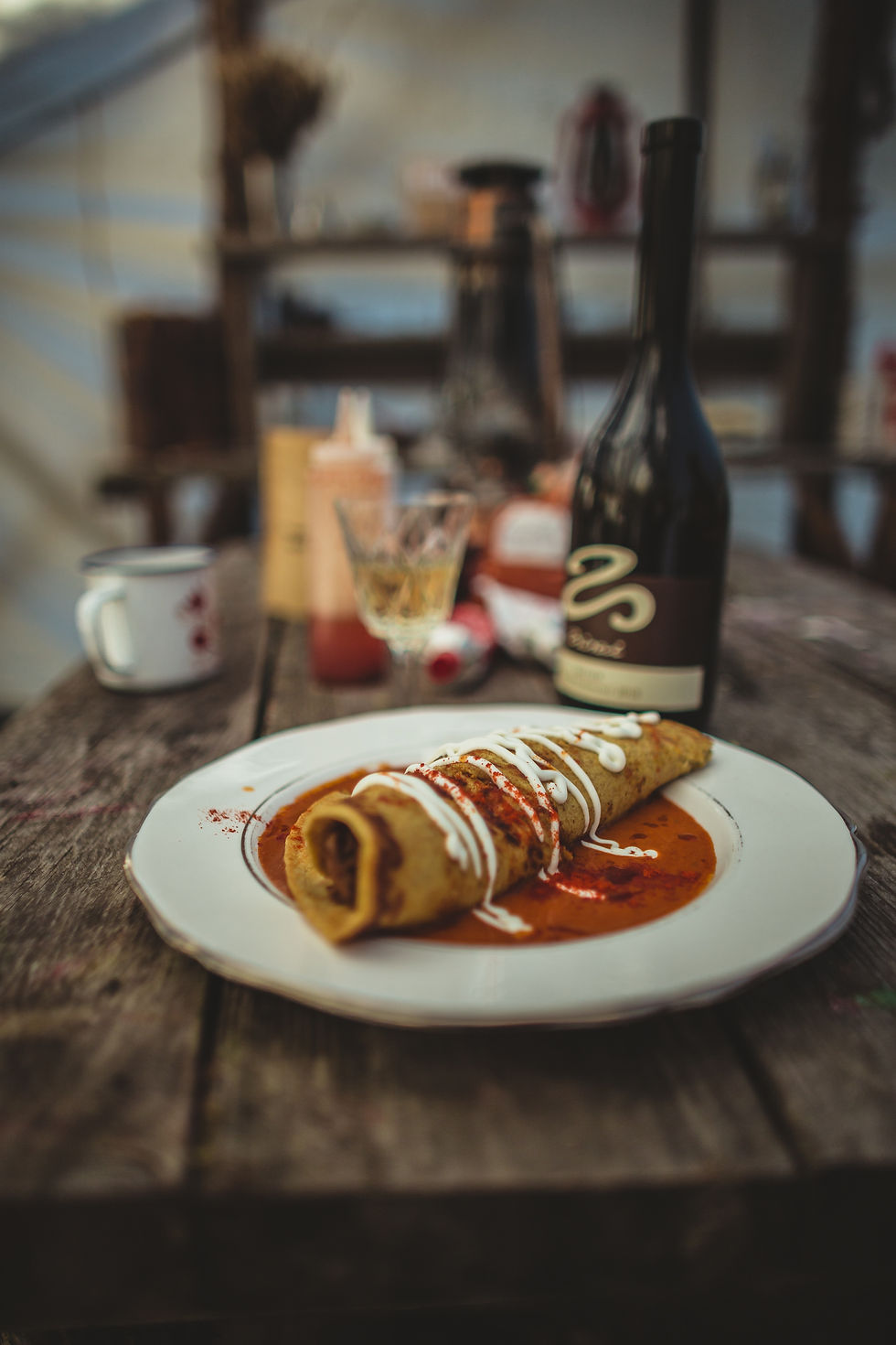 A beautifully plated food dish sits on a rustic table inside the wall tent. 