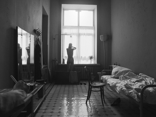 Naked woman by window in a stark, Dystopia Feature Film setting.