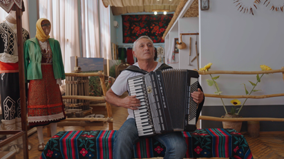 Man playing accordion on patterned bench in cultural museum.