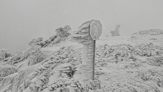 Icy mountain landscape with wind-swept, ice-covered sign