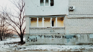 War-damaged building with 'We were here once...' graffiti.