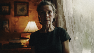 Somber woman looking intently in dimly lit room for Dystopia Feature Film.