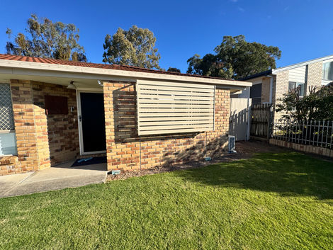 Paperbark aluminium slat screen fitted over a window on a brick home.