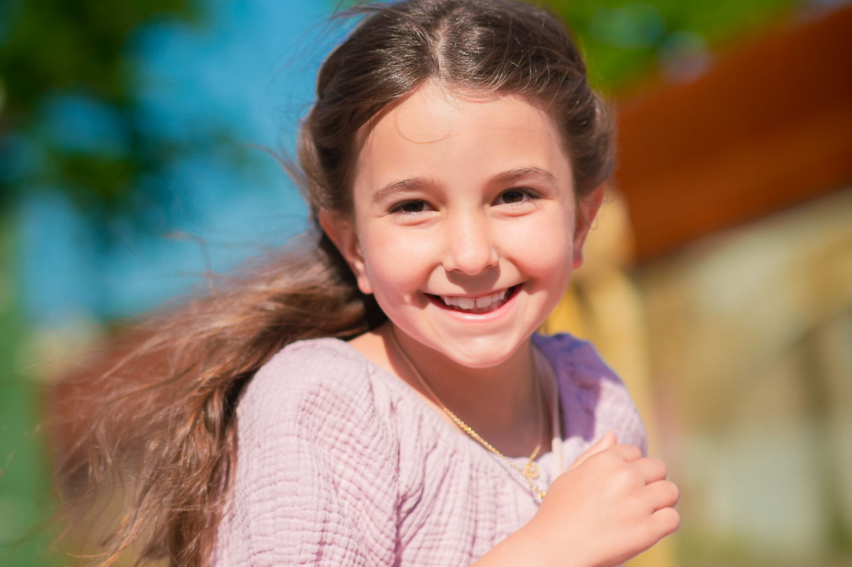 Portrait d’une petite fille souriante en extérieur, séance photo enfant naturelle – Brin de Lune photographe à Nantes