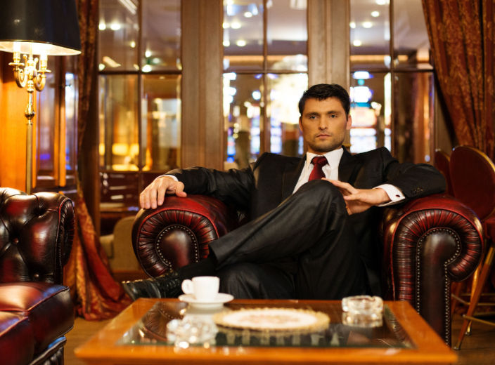 A man in a suit sits confidently in a luxurious room with leather chairs and soft lighting. Stockholm Meditation. Meditation teachers.