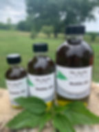 Three bottles of Nettle Oil, My herbs for you, with green leaves in front.