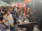 Here’s a cleaner, polished version of the alt text only:
**Crowded booth with our dedicated CTO happily explaining the silicone tool on the Prusa XL printer.**