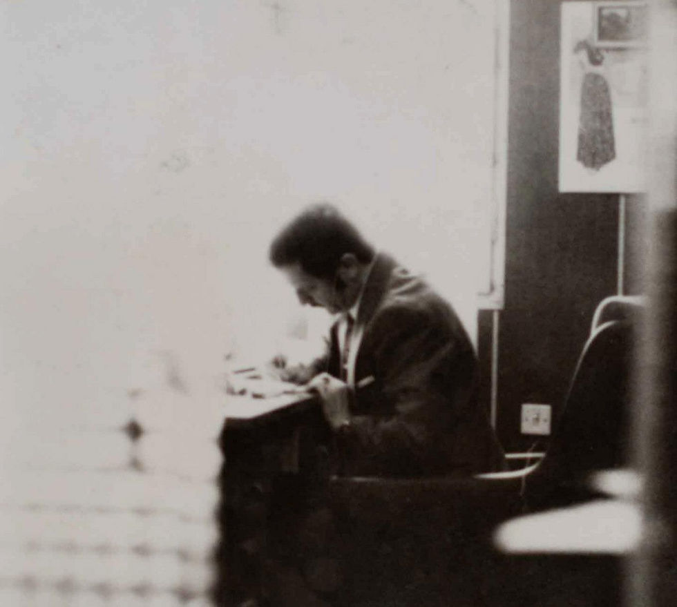 A black and white old photo of a man drawing plaid patterns on a desk