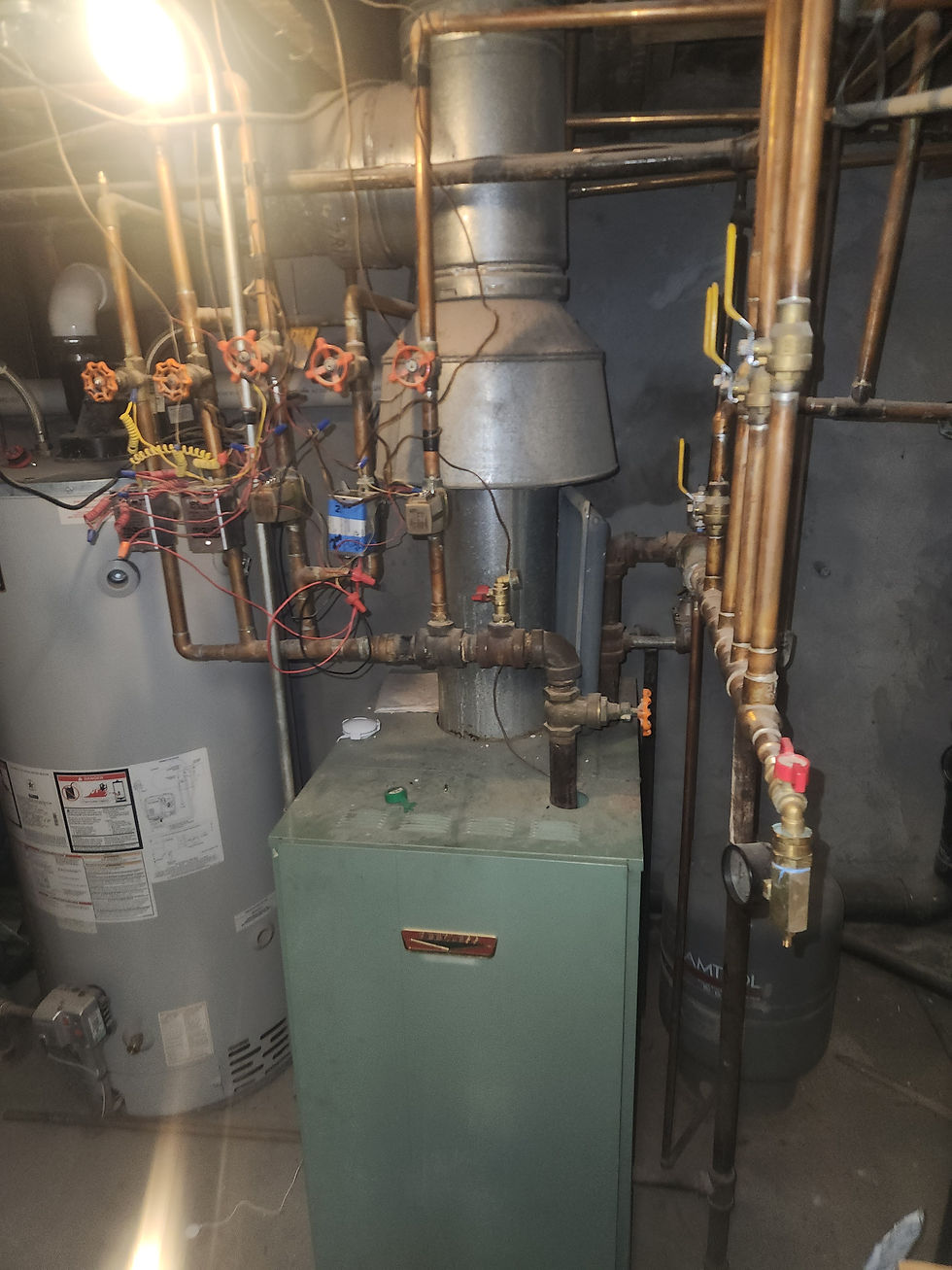 Existing atmospheric-vented boiler with galvanized draft hood, aged copper piping and zone valves before replacement
