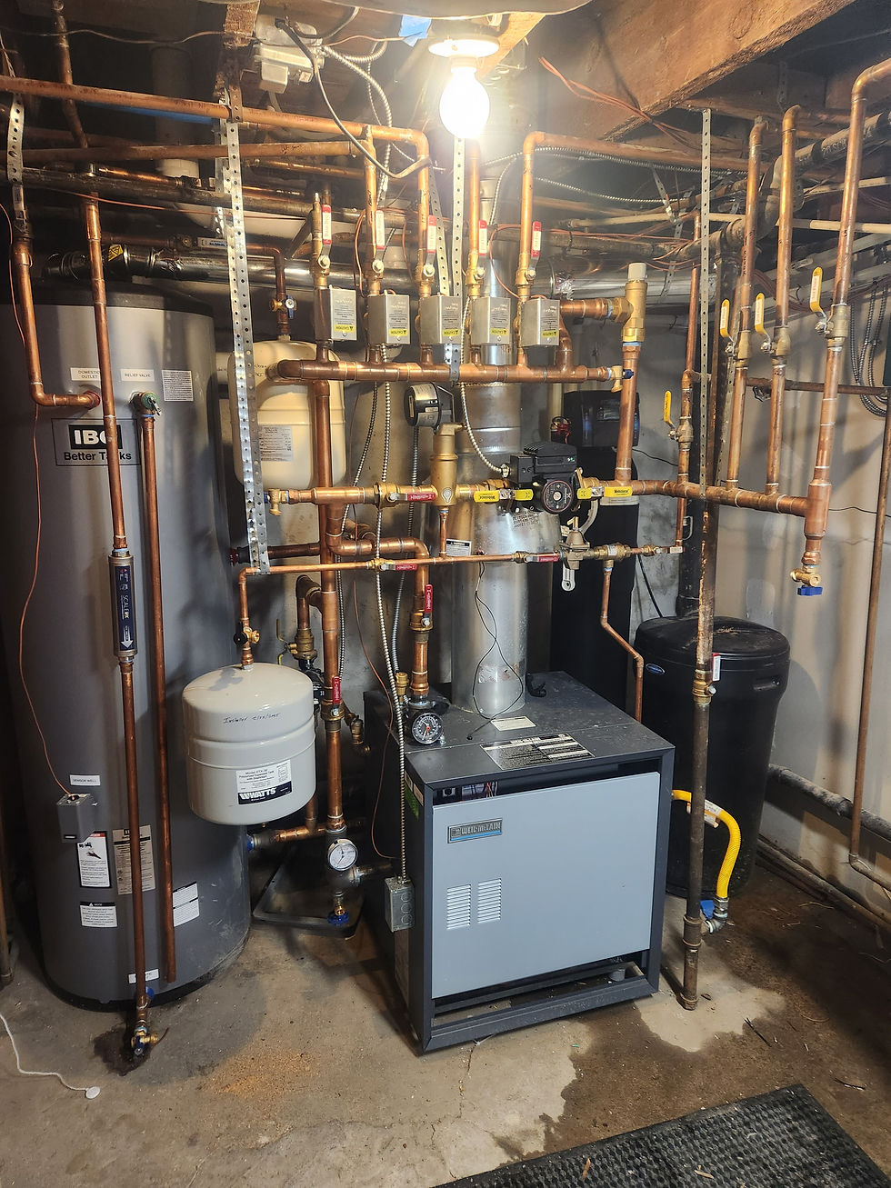 Copper near-boiler piping with four zone valves, expansion tank, air separator and circulator beside an indirect tank