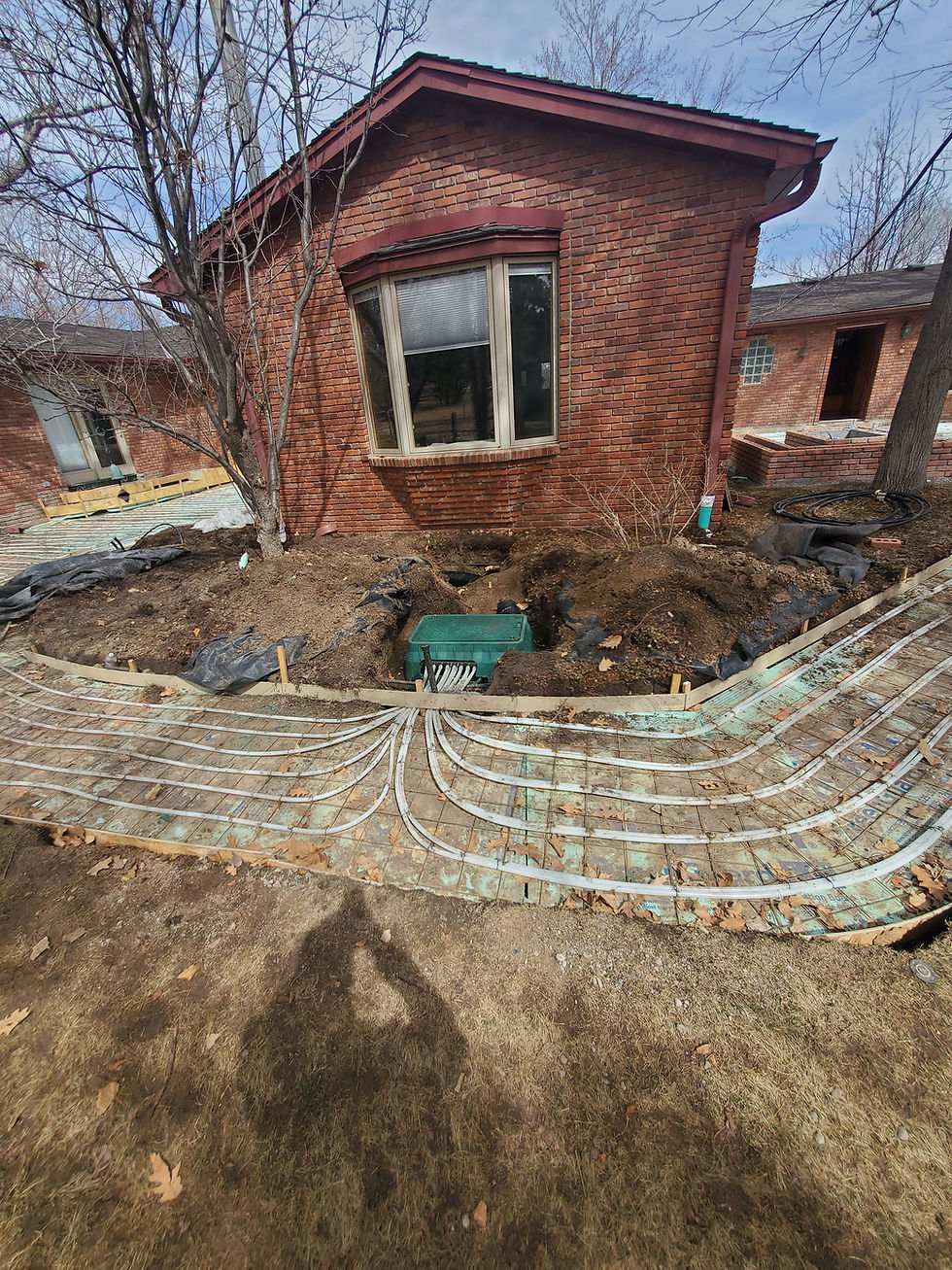 In-ground snowmelt manifold vault with PEX loops fanning out to formed patio and walkway areas before the concrete pour