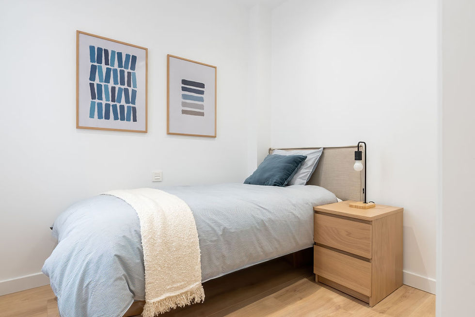 Habitación sencilla con cama individual, mesita de noche y cuadros