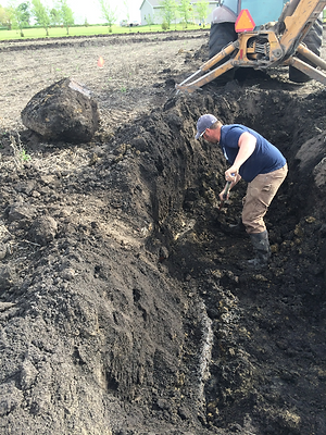 digging a new, straight trench to lay this section of tile in.