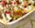 Plate of nachos topped with green, white, and brown sauces, pomegranate seeds, and crispy strips. Visible text: "Salsa Samosa."
