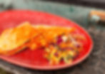 Salsa Samosa's Quesadillas and coleslaw on a vibrant red plate, set against a textured metal surface. Bright and appetizing colors emphasize freshness.