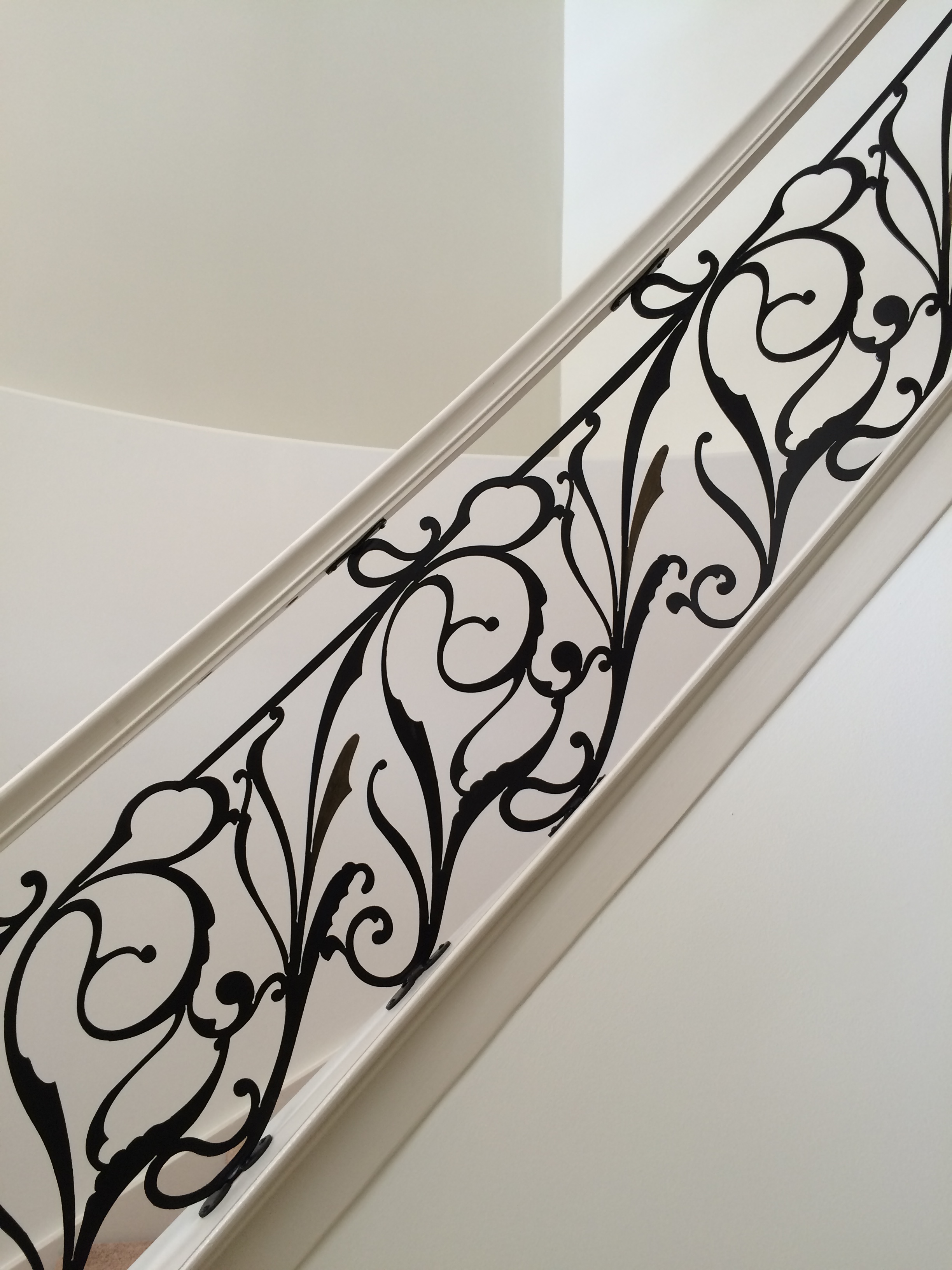 Interior iron railing with elegant floral scrollwork on a curved staircase.