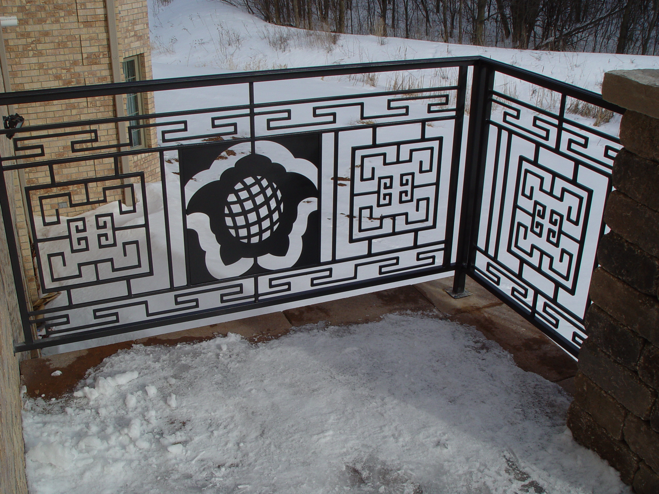 Exterior iron railing with geometric borders and floral medallions.