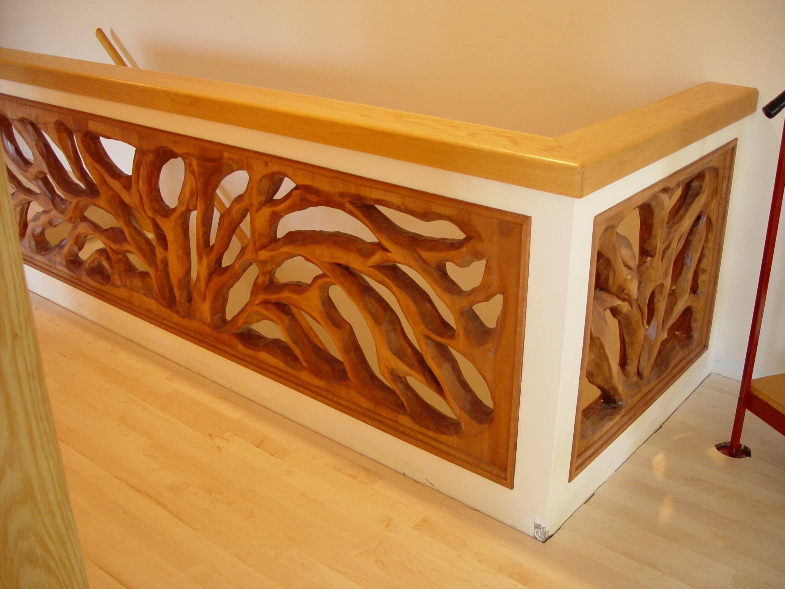 Hand-carved wooden interior railing with flowing tree-inspired forms.