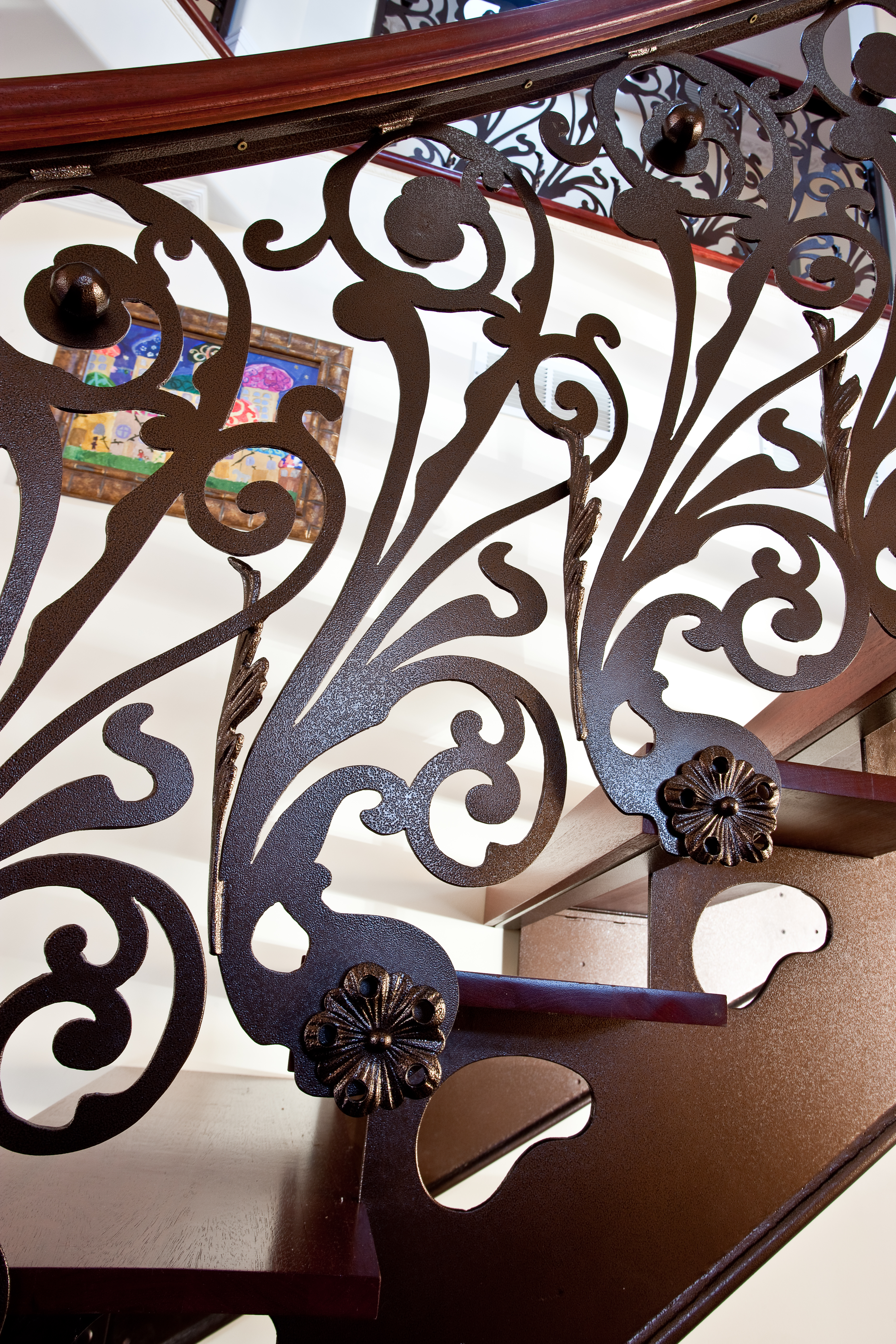 Detailed interior railing with botanical scrollwork and a polished wood handrail.