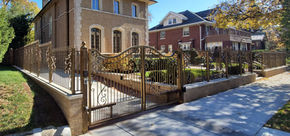 Elegant gold-tone wrought iron gate and fence with ornate scrollwork.