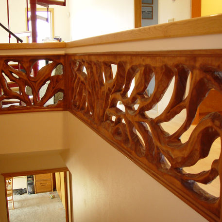 Hand-carved wooden interior railing with flowing tree-inspired forms.