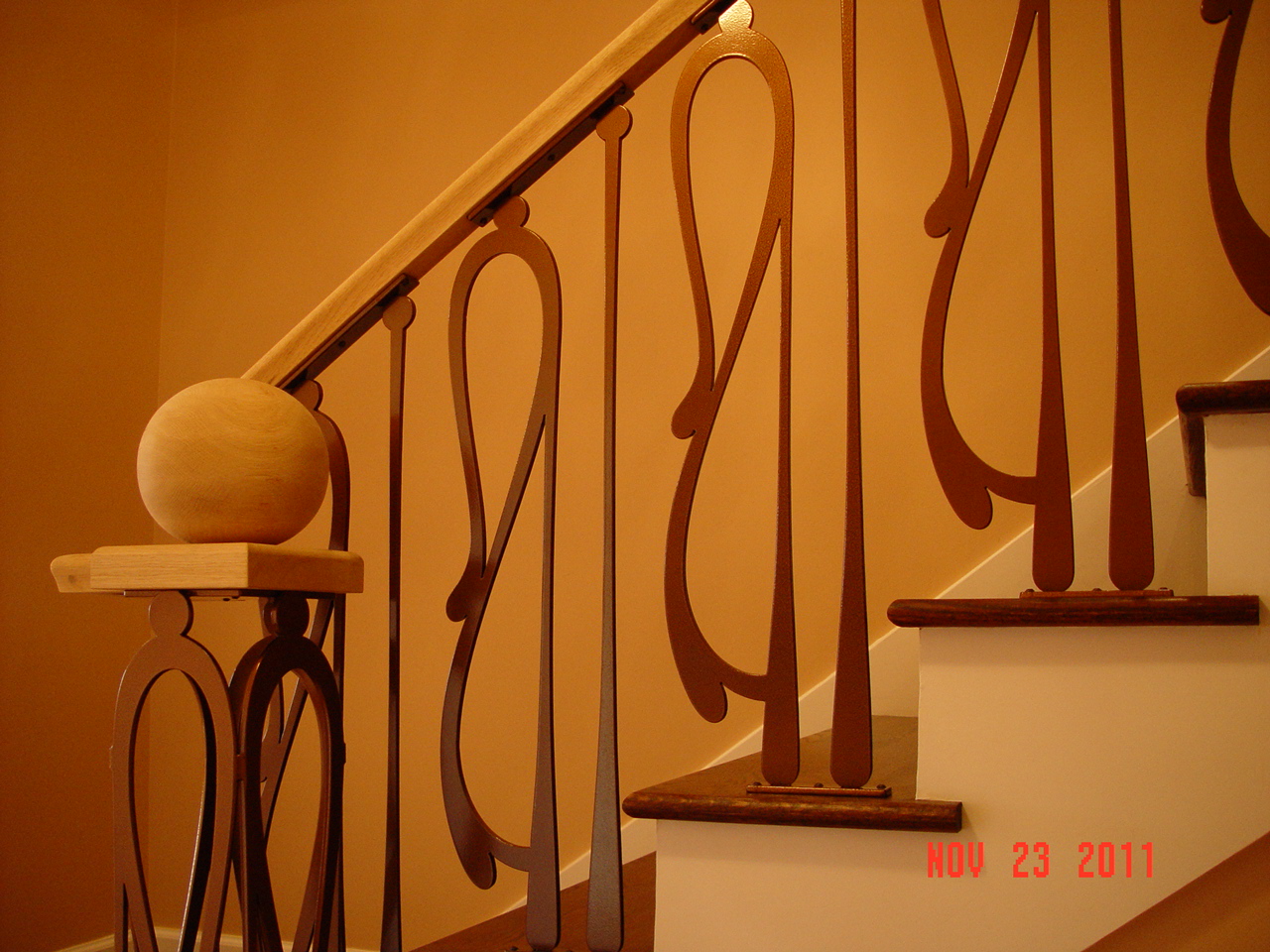 Contemporary interior iron railing with elongated musical forms and a wood handrail.