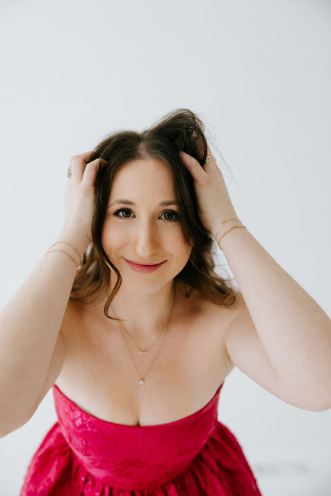Woman in pink strapless dress posing with hands in hair.