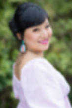 Smiling woman with dark hair and colorful earrings