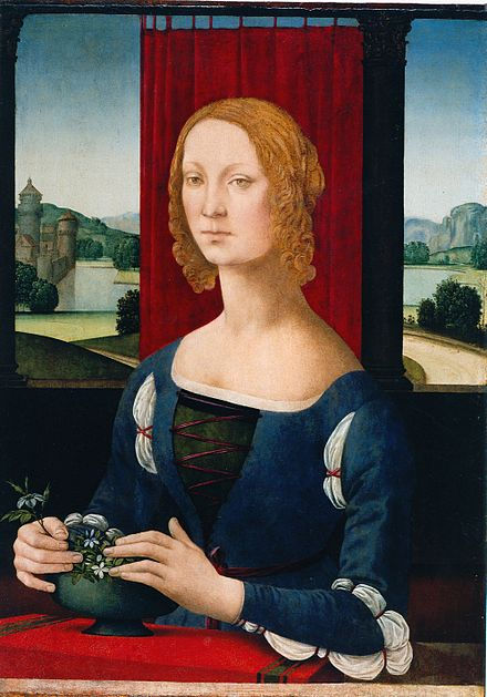 Presumed portrait of Caterina Sforza in a blue dress holds a vase with greenery. She sits before a red curtain, with a landscape of trees and water visible outside.
