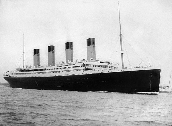 Large ocean liner with four smokestacks sails on calm sea. Black and white image, early 20th-century design, serene atmosphere. A black and white image showing the RMS Titanic departing Southampton for the first and only time on 10 April 1912