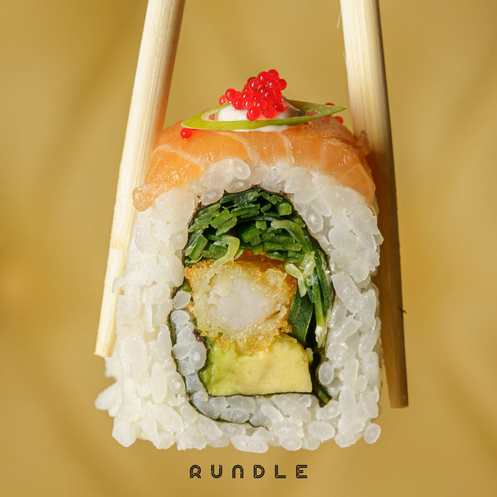 A close-up shot of a sushi roll lifted up by chopsticks - Restaurant Photography  