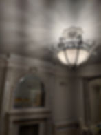 Ornate chandelier illuminates a room with a fireplace and mirror My Site 1