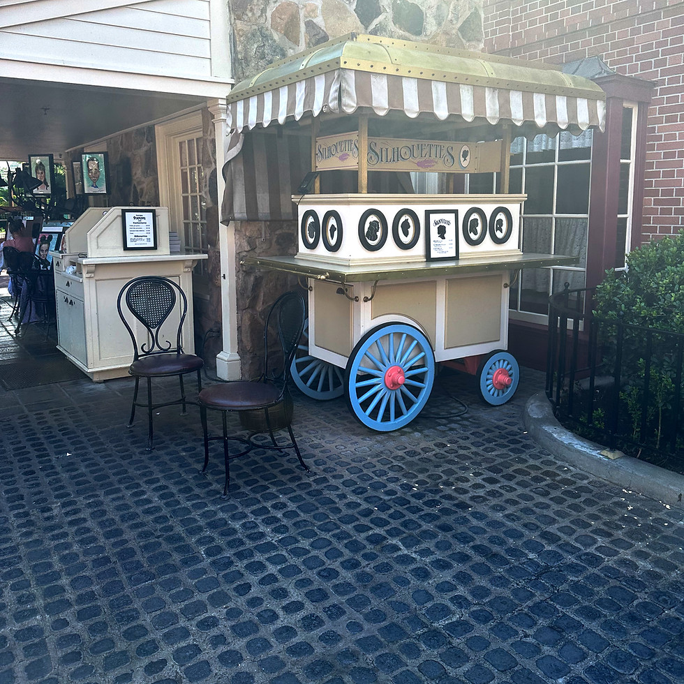 Liberty Square Portrait Gallery cart with gold and white awning and black framed silhouettes.