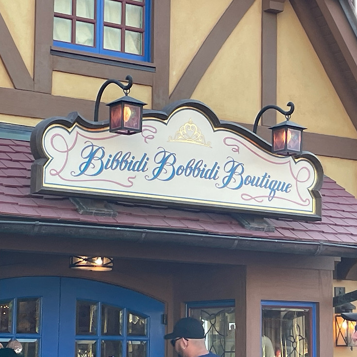 Bibbidi Bobbidi Boutique entrance at Magic Kingdom, with a royal sign adorned in gold script and magical stars, welcoming young guests for princess makeovers.