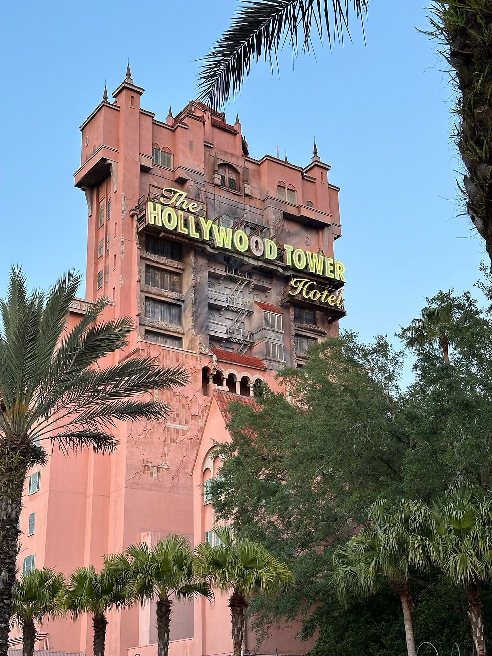 Weathered Hollywood Tower Hotel facade with broken windows, art deco design, and the iconic “Tower of Terror” sign amid eerie landscaping.