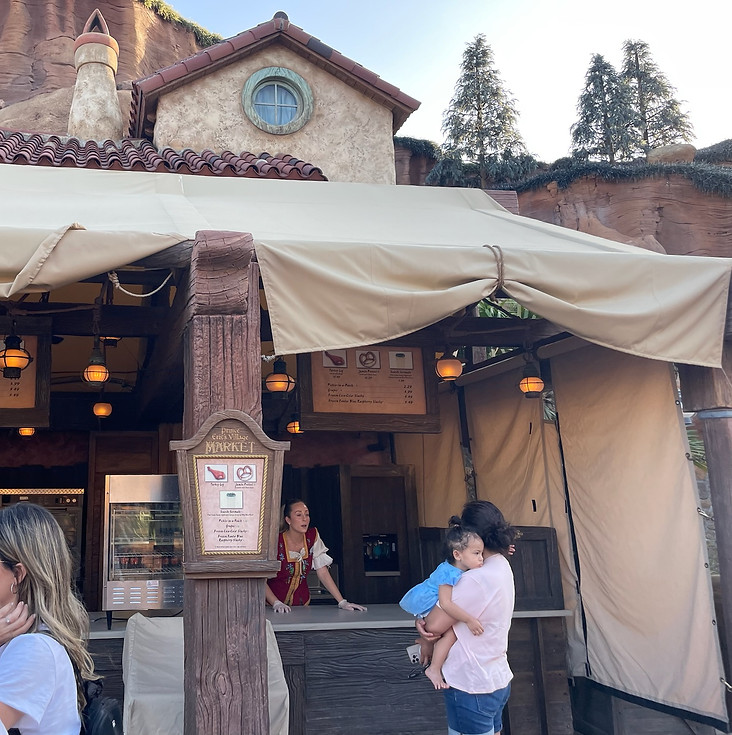 Prince Eric’s Village Market in Fantasyland, a seaside-themed market stall with rustic wood accents and a medieval castle-inspired setting.
