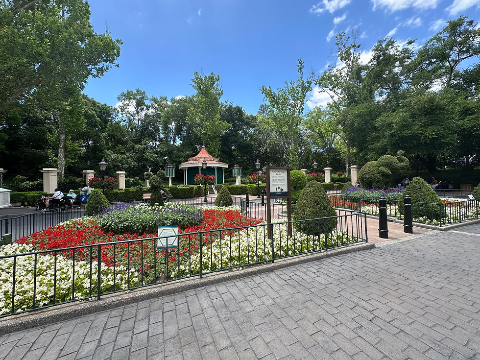 White Gazebo with red and fowers, trees, and black iron fence