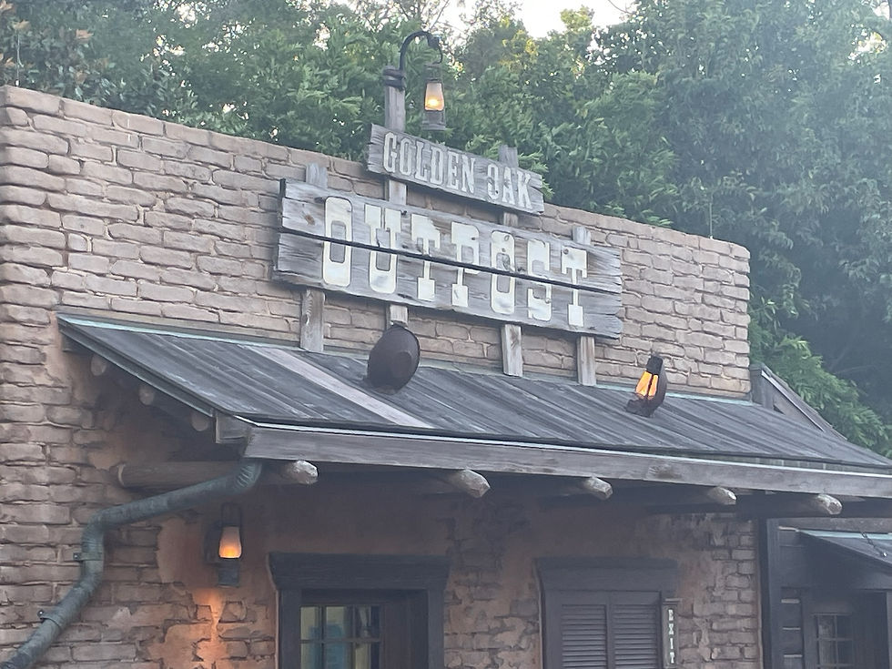 Golden Oak Outpost in Frontierland, a small log-cabin-style snack stand with a frontier theme, lanterns, and a wooden sign hanging above the awning.