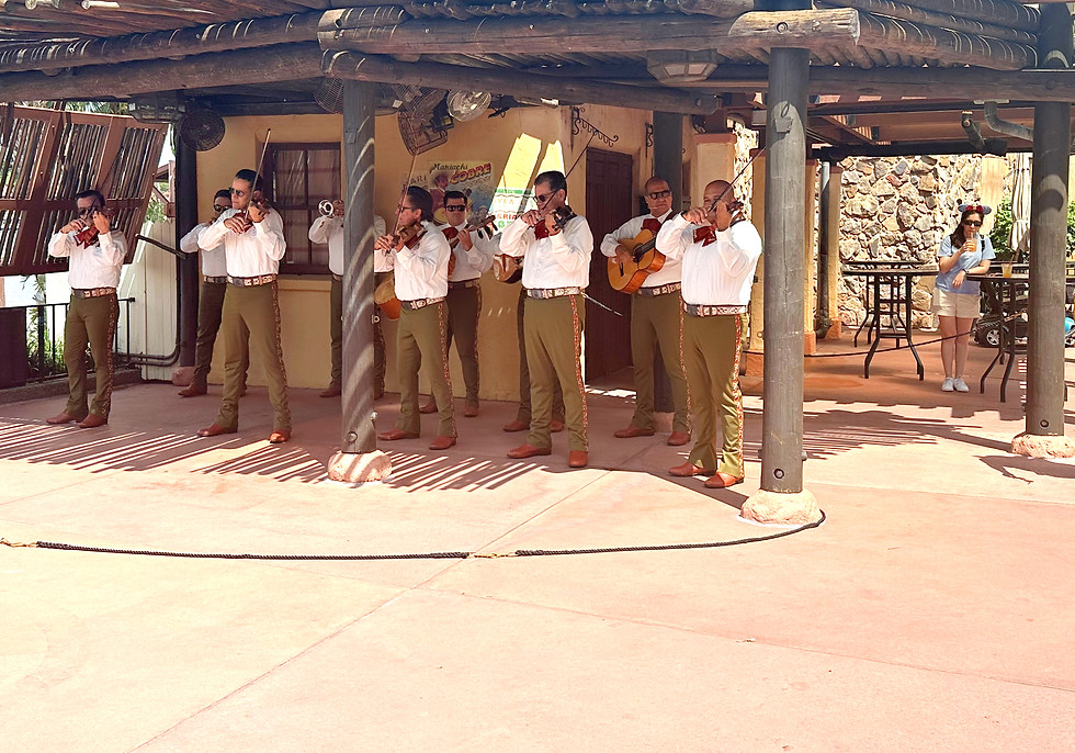 Mariachi Cobre performing with various instruments under a wooden structure